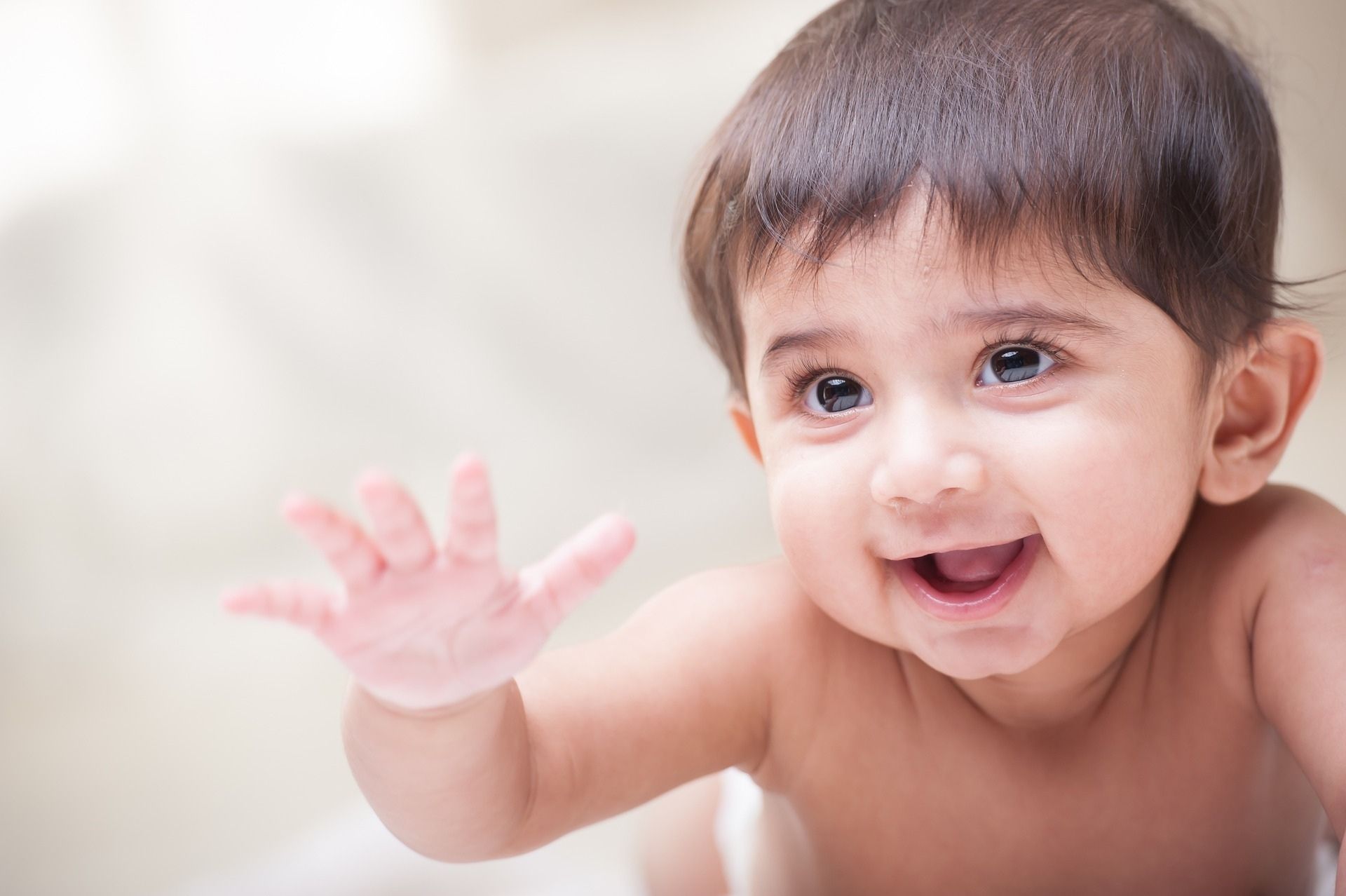 Un enfant de quelques mois qui tend la main et qui sourit