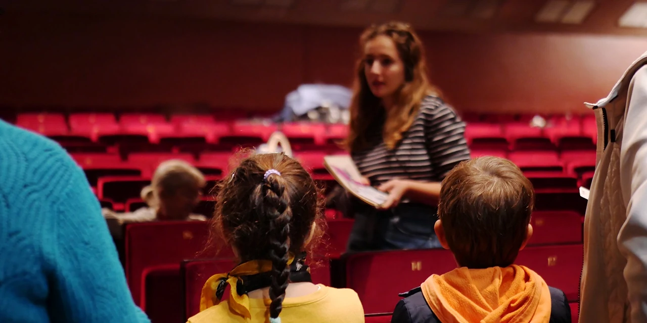 Deux enfants écoutent une guide faire la visite du Grand Théâtre.