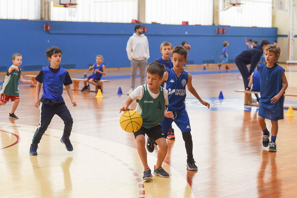 Des jeunes jouent au basket dans un gymnase.