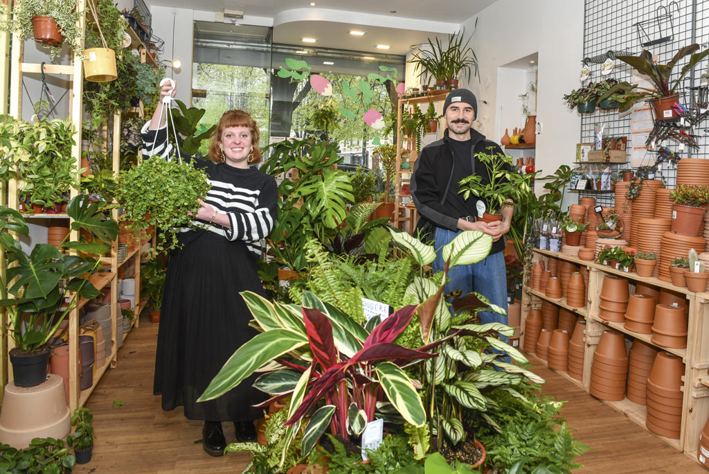 Les gérants de la boutique posent parmi des plantes.