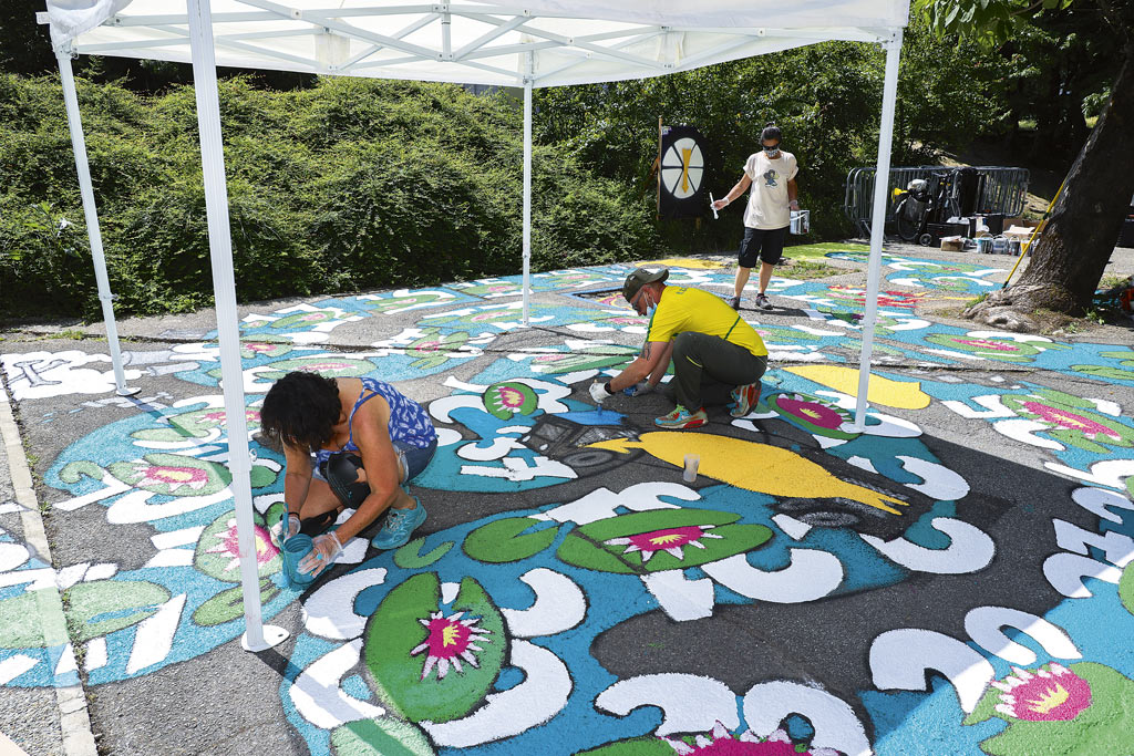 Des personnes peignent une fresque au sol dans le cadre d'un chantier participatif.