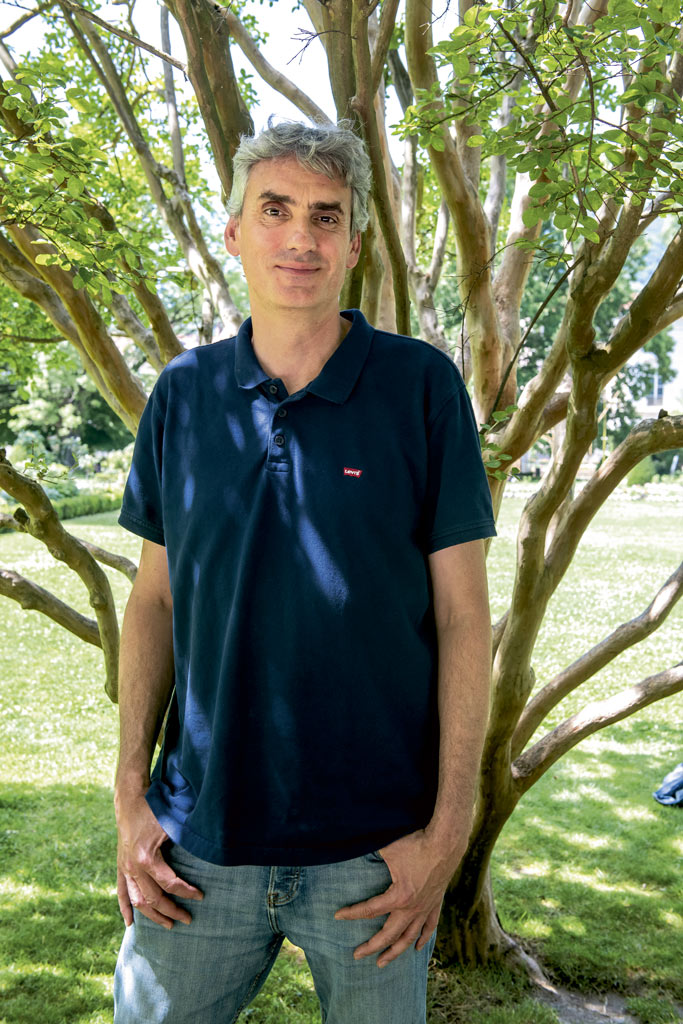 Gilles Namur pose devant un arbre.