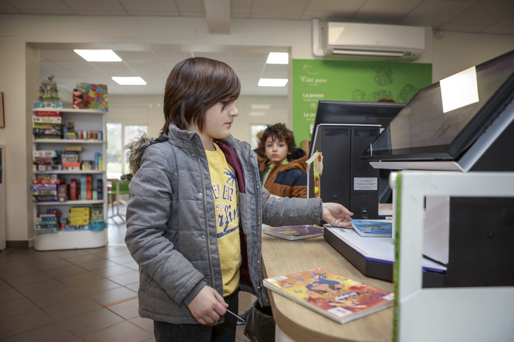 Un enfant utilise les machine pour enregistrer ses emprunts.