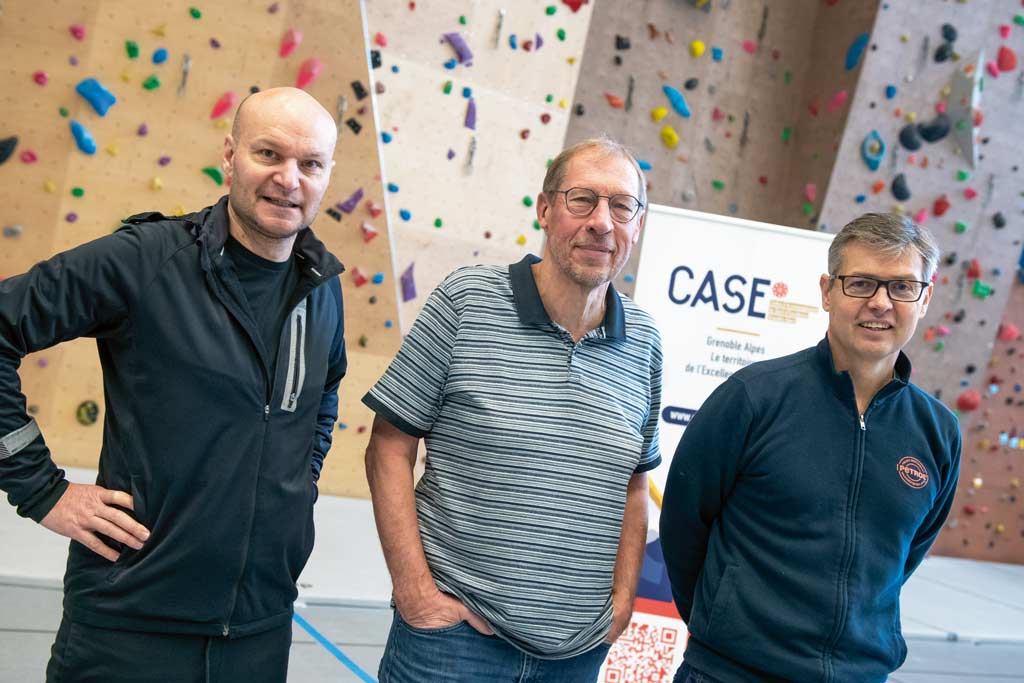 Trois représentants posent devant un mur d'escalade.