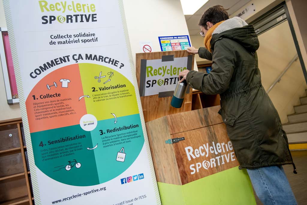 Une femme met une gourde dans une boîte appelée ecobox.