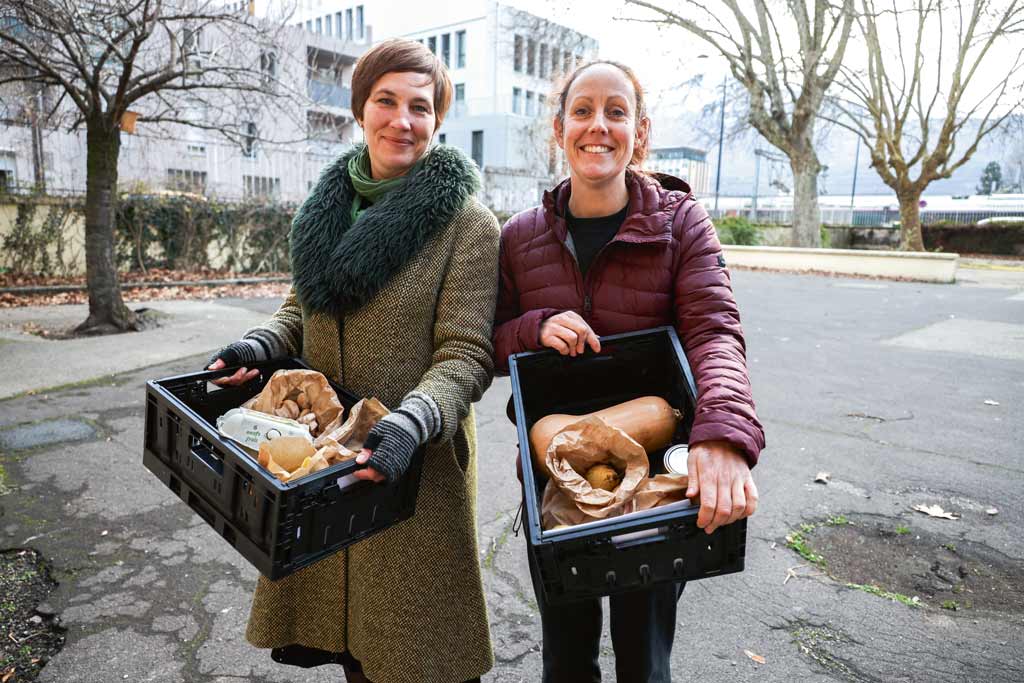 Marion Pinault et Lydie Desplanques portent des cagettes de légumes.