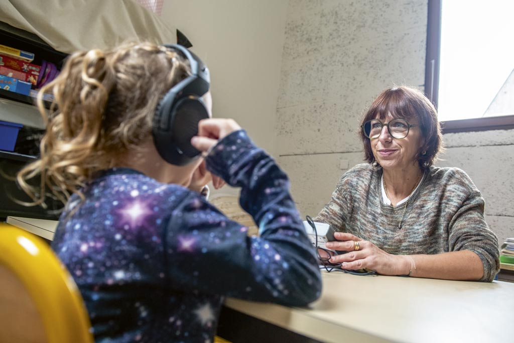 Une infirmière scolaire réalise un test auditif à une petite fille.