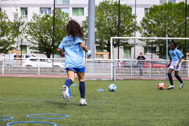 Une jeune fille en tenue de football court sur un terrain de football.