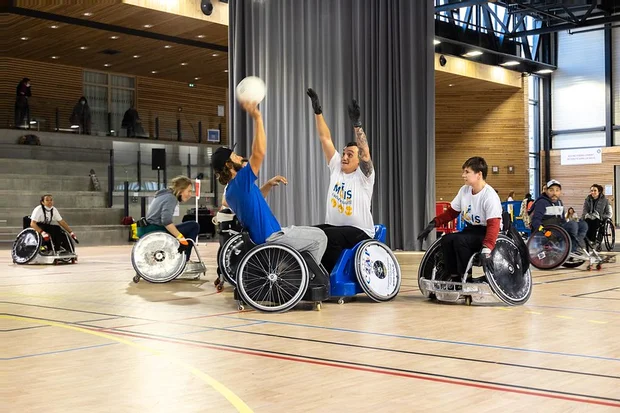 Match de torball en fauteuil au Centre sportif Jean-Philippe Motte. Deux athlètes en fauteuil se disputent la balle en l'air.